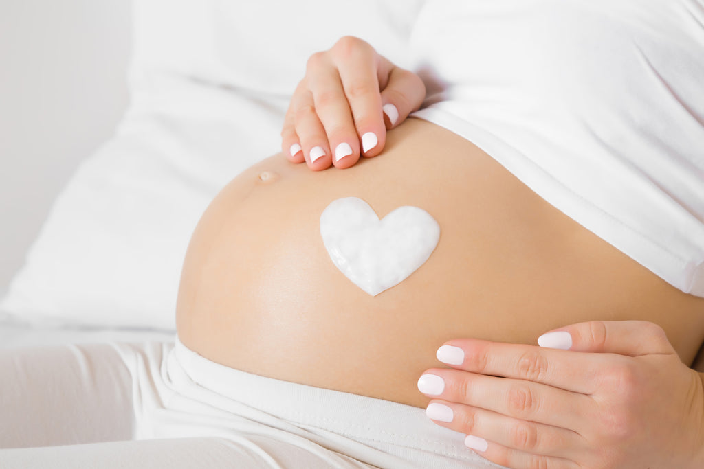 Pregnant woman holding her bump with heart shape on bump